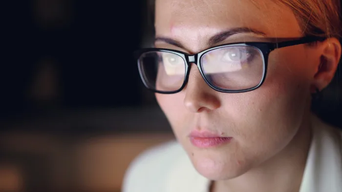 Photograph of a woman staring at a computer screen as it appears reflected in her eyes